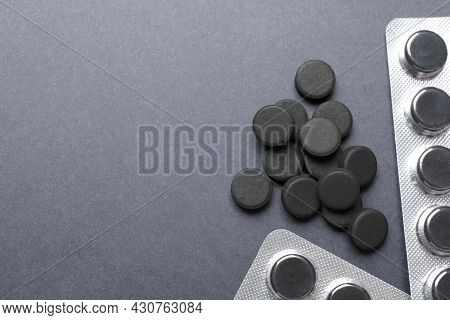 Activated Charcoal Pills On Grey Background, Flat Lay With Space For Text. Potent Sorbent