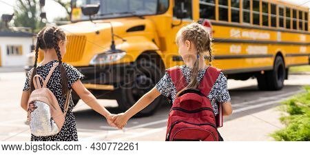 Cheerful Little Girls Next To School Bus. Backback. Back To School Concept.