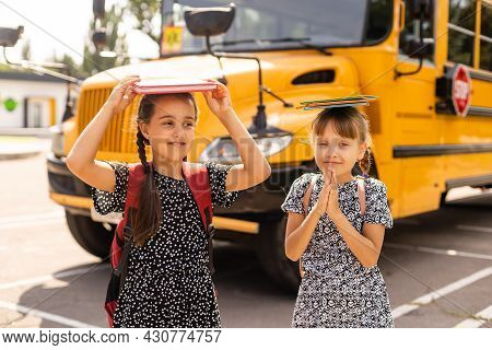 Cheerful Little Girls Next To School Bus. Backback. Back To School Concept.