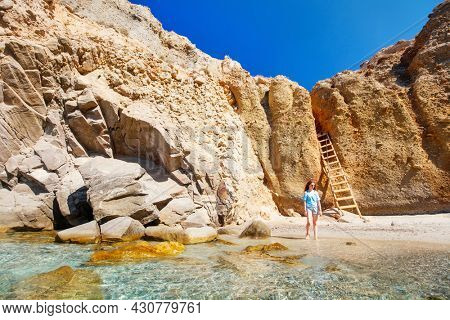 Cute girl enjoying secluded Tsigrado beach surrounded by amazing cliffs on Greek island of Milos