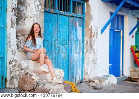 Adorable teenage girl enjoying visit to colorful fishing village of Klima on the island of Milos in Greece