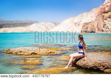 Cute  girl enjoying idyllic Fyriplaka beach surrounded by amazing cliffs on Greek island of Milos