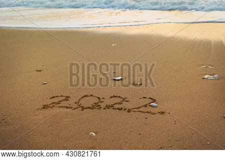 2022 Happy New Year Inscription Sand Beach. The Written Text Is Written On Yellow Sand And Is Washed