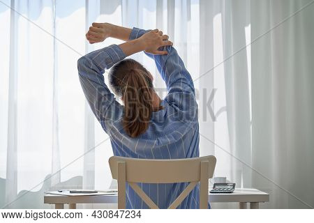 Back View Of Young Faceless Woman In Casual Clothes Stretching. Remote Work Challenges And Disadvant