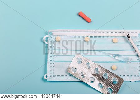 Health Protection And Medicine. Medical Mask, Blister Of Pills, Ampoule, Syringe On A Blue Backgroun