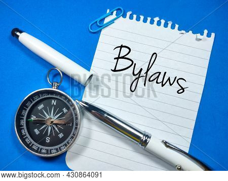 Business Concept.text Bylaws Writing On Notepaper With Open Pen And Compass On Blue Background.