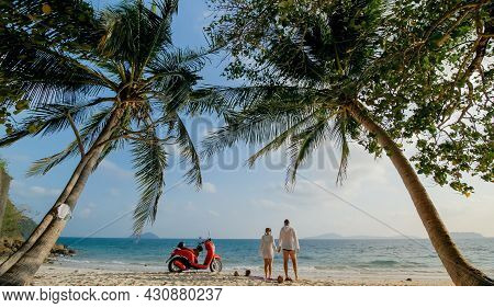 Scooter Road Trip. Lovely Couple On Red Motorbike In White Clothes On Sand Beach. People Walking Nea