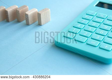 Mint Calculator And Stacks Of Wooden Cubes On Blue Background