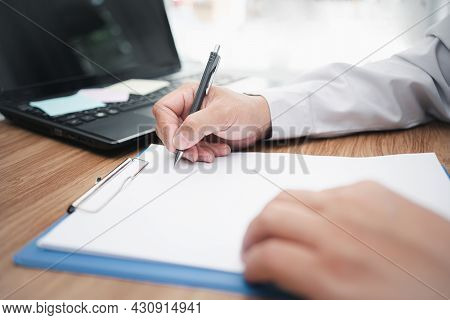 Man Use Pencil White Document On Table And Use Laptop Computer In Background