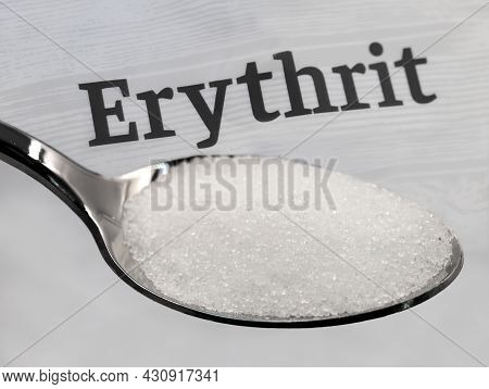 Silver Spoon With Crystalline Erythritol Sugar In Front Of The Word Erythrit