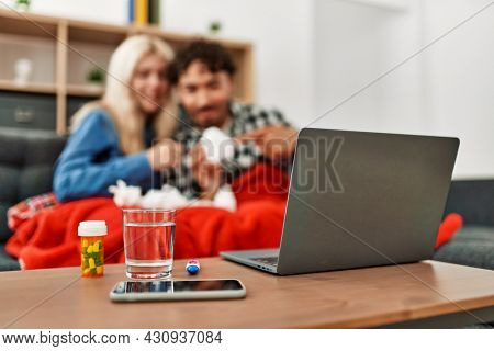 Young ill couple having medical teleconsultation using laptop at home.