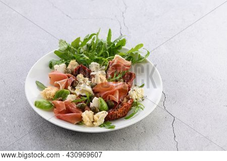 Salad Arugula, Parma Ham With Sun-dried Tomatoes, Mozzarella Slices, Croutons, Capers, Seasoned Oil 