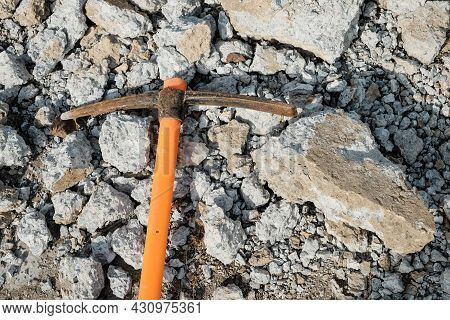 Pickaxe Hoe Lying On Crushed Stones. Hand-held Percussion Tool Designed For Working On Stone, Stony 