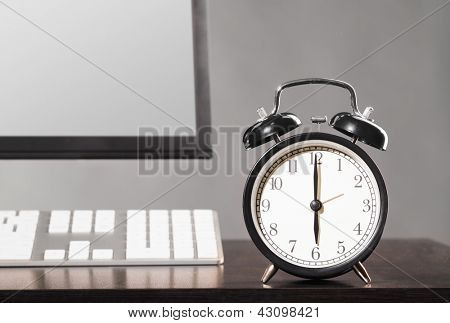 einde van de werkdag. computer op kantoor met klok op grijze achtergrond