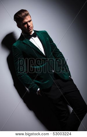 man in green suit with bow tie looks at the camera on gray background