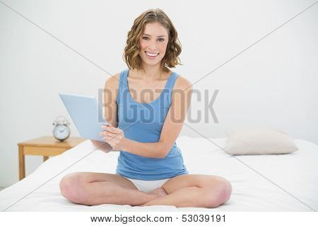 Beautiful cheerful woman smiling at camera while holding her tablet and looking at camera