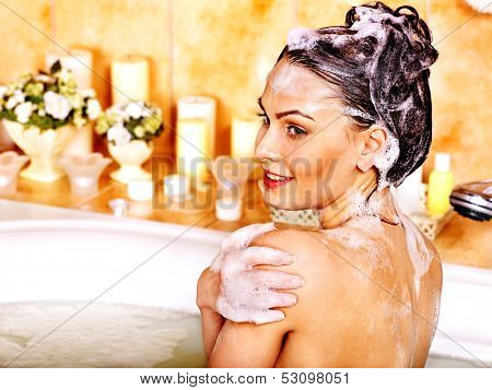 Yong woman washing hair in bubble bath.