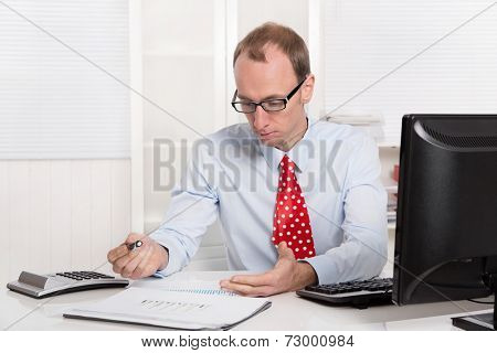 Quizzically engineer or specialist in shirt and tie sitting at desk 
