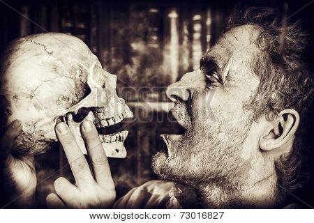 Close-up portrait of an old medieval scientist holding a skull. Alchemist. Halloween.