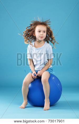 5 years old child playing with fitball l on blue studio background