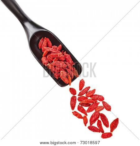 Goji berries. The addition to the tea beverage in black wooden scoop , isolated on white background