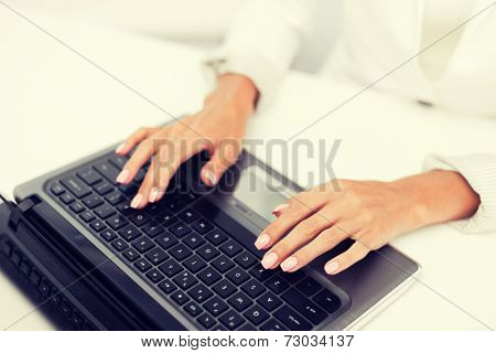office, business, technology and internet concept - businesswoman using her laptop computer