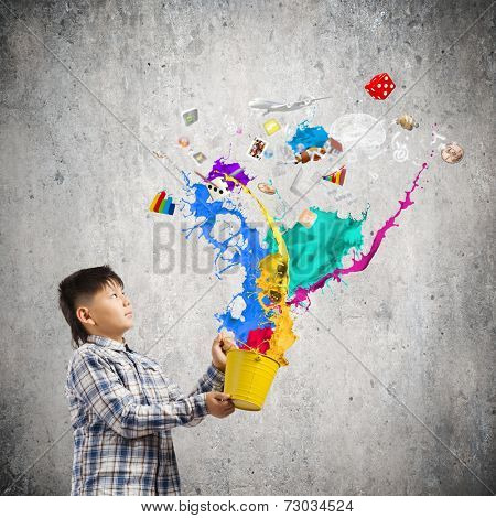 Young boy splashing colorful paint from bucket