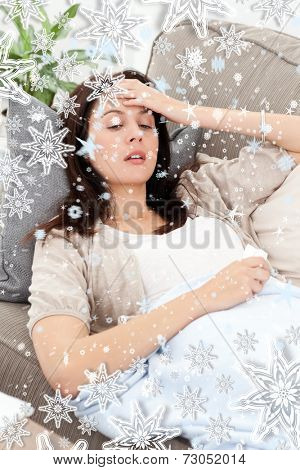 Sick woman lying on the sofa and touching her forehead against snow falling