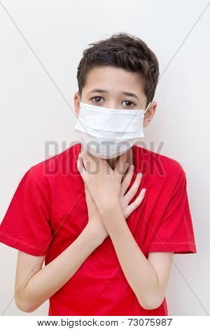  A sick young boy clutches his throat with face mask on.