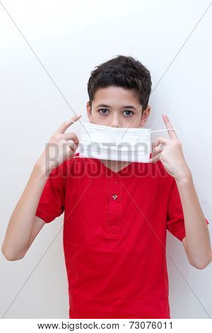  A sick young boy putting on a face mask to stop spread of germs.