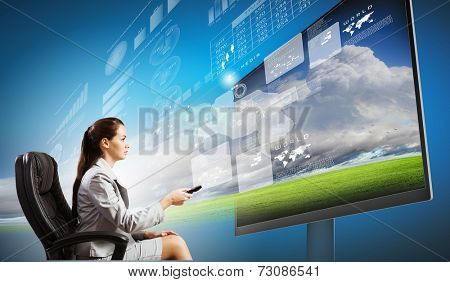 Young businesswoman in chair near tv screen with click