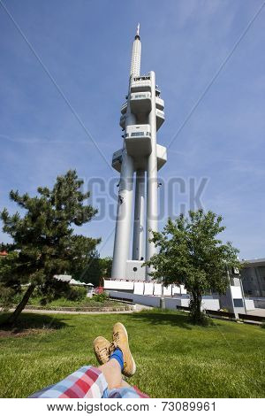 Low section of man relaxing in front of Zizkov Television Tower in Prague; Czech Republic
