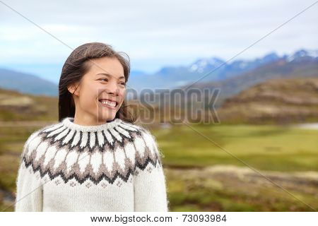 Woman on Iceland in Icelandic sweater. Portrait of girl happy smiling outdoors in nature wearing Icelandic sweater. Pretty Asian Caucasian multiracial female model