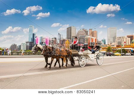 MELBOURNE, AUSTRALIA - JAN 15,2015: Coach with tourists crossing the bridge on Jan 15, 2015 in Melbourne, Australia. Horse carriage is a popular way for sightseeing in Melbourne.