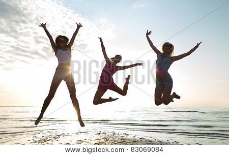 friendship, summer vacation, freedom, happiness and people concept - group of happy female friends dancing and jumping on beach