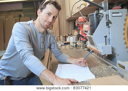 An adult carpenter measuring wood with ruler at table in worksho