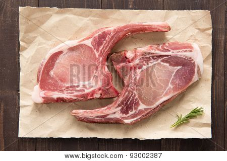 Top View Raw Pork Chop Steak On Paper On Wooden Background