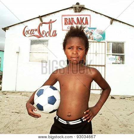 Boy posing with a ball in township, South Africa.