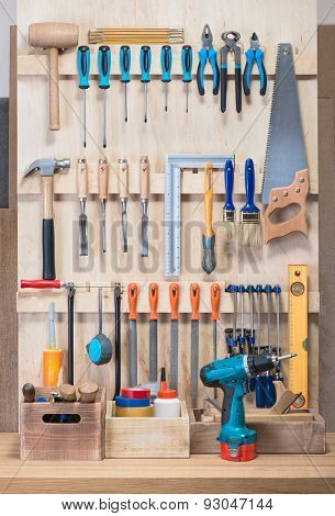 Garage tool rack with various tools and repair supplies on board and shelves.