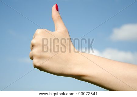 Hand girl showing thumbs up against the sky