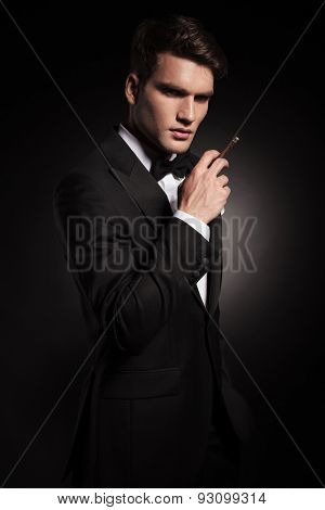 Young elegant man looking at the camera while holding a cigarette in his hand.