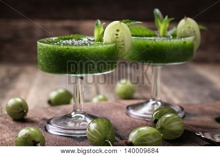 Healthy green fresh fruit and vegetable juice smoothie breackfast with chia seeds garnish and green gooseberry.