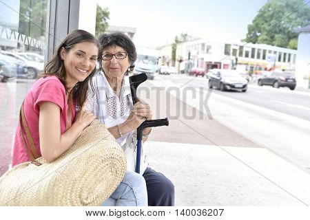 Senior woman with home carer waiting for the bus