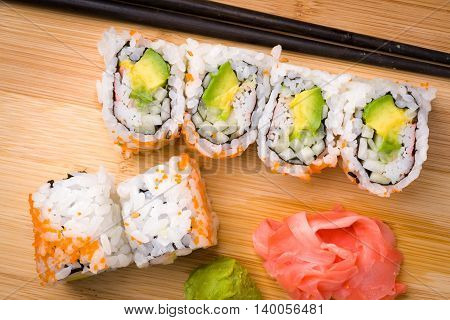 Sushi California rolls appetizer with rice avocado with chopsticks