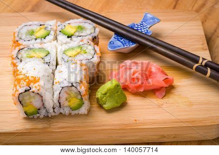 Sushi California rolls appetizer with rice avocado with chopsticks