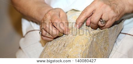 Hands Of The Elderly While Embroidering A Lace