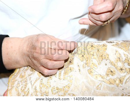 Hands Of The Elderly While Embroidering A Lace With Lace Pillow