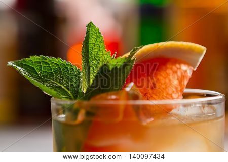 Cocktail with slice of grapefruit. Green leaves of mint. Exotic drink named Cobas. Chilled whiskey and fresh juice.