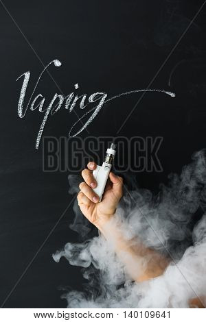 Electronic cigarette in hand vaper on a dark background with smoke. New subculture vaping concept.