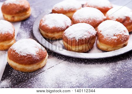 German donuts - berliner with jam and icing sugar in a tray on a dark wooden background. Space for text